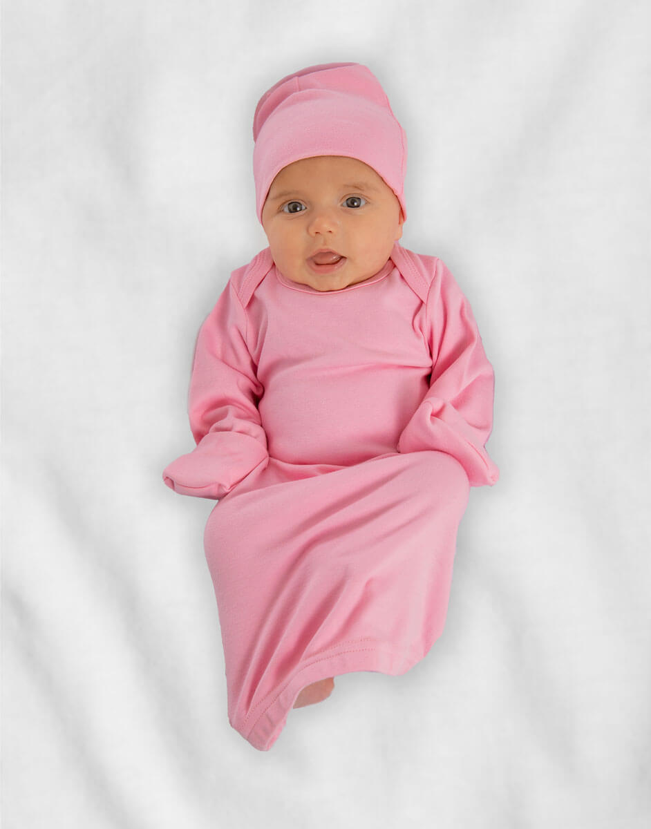 Baby wearing pink layette gown and cap