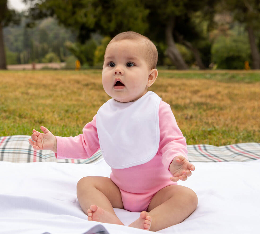 baby wearing white velcro bib and pink onesie